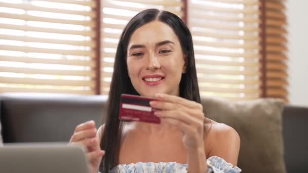 Genç bir kadın internet bankacılığı için kredi kartıyla dizüstü bilgisayar kullanıyor. Evinde online ödeme kapısı ile E ticareti yapıyor. Banka kartıyla modern ve kullanışlı online satın alma. Blithe - Video, Çekim