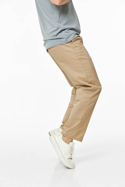 man wearing white sneakers and casual beige pants on studio background. side view - Фото, зображення