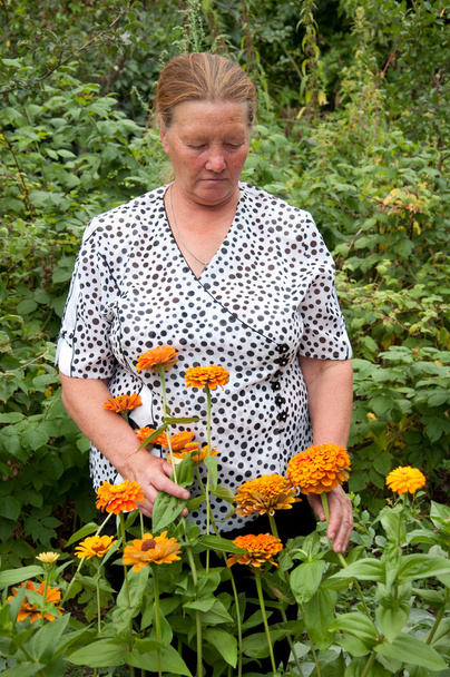 Pensioner takes care of the flowers in the garden at the cottage - Foto, Imagen