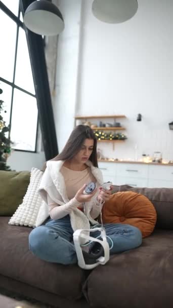 En la alegría navideña, una encantadora joven inspecciona su regalo: un auricular VR. Imágenes de alta calidad 4k - Metraje, vídeo