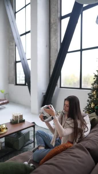 Окруженная рождественскими радостями, очаровательная молодая женщина осматривает свой подарок - гарнитуру виртуальной реальности. Высококачественные 4k кадры - Кадры, видео