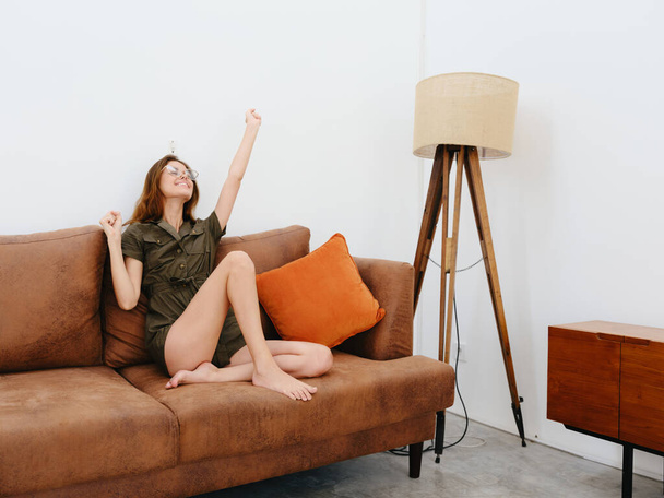 Женщина модель сидит на диване дома улыбаясь, вдумчивый и расслабленный, современный стиль жизни интерьера, копировать пространство, палитра осеннего цвета. Высокое качество фото - Фото, изображение