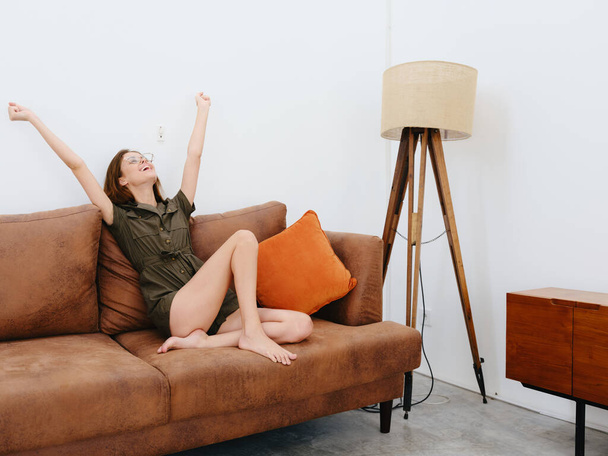 Žena model sedí na gauči doma úsměv, překvapení, radost a relaxace, moderní vnitřní životní styl, kopírovací prostor, podzimní barevná paleta. Kvalitní fotografie - Fotografie, Obrázek