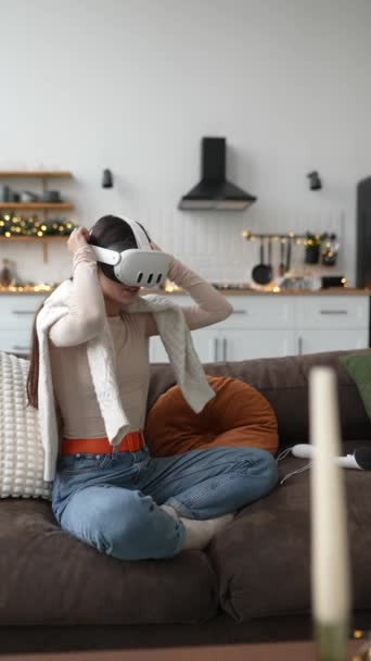 En medio del ambiente festivo, una hermosa joven inspecciona su regalo: un auricular VR. Imágenes de alta calidad 4k - Imágenes, Vídeo