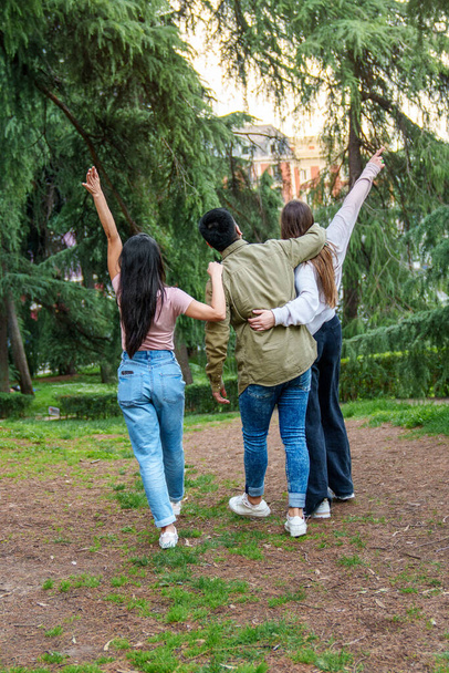 Három barát élvezi a sétát a természetben, átöleli és örömteli gesztusokkal ünnepli köteléküket.. - Fotó, kép