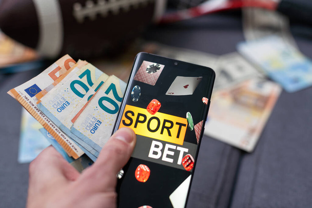 Smartphone με εφαρμογές για κινητά τυχερά παιχνίδια, χαρτονομίσματα μπάλα και χρήματα. Έννοια αθλητισμού και στοιχήματος. - Φωτογραφία, εικόνα