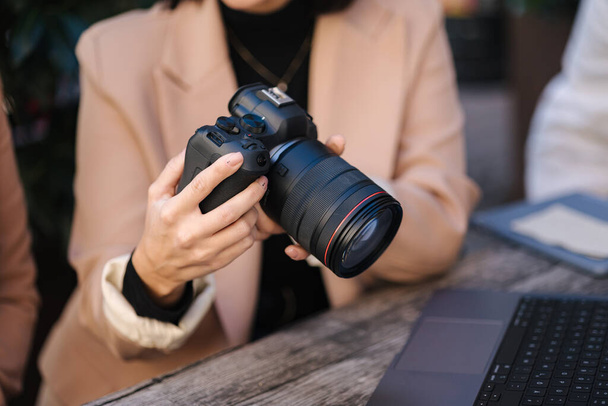 Close-up of photographer holding mirrorless camera and checking pictures. . High quality photo - Foto, Imagen