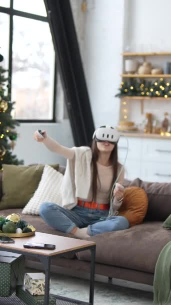 U vánočního stromku sedí mladá a atraktivní žena a hraje videohry se sluchátky virtuální reality. Vysoce kvalitní 4K záběry - Záběry, video