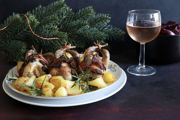 Baked quails with potatoes and herbs on a festive background. Christmas and holiday season. Copy space. - Photo, Image