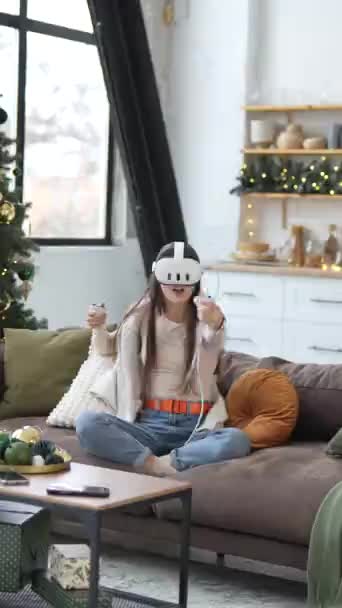 U vánočního stromku sedí mladá a atraktivní dáma a hraje videohry s pomocí sluchátek virtuální reality. Vysoce kvalitní 4K záběry - Záběry, video