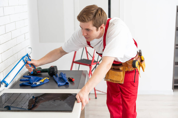 craftsman installs hob in kitchen. Household Appliance Installation Services Concept. - Фото, изображение