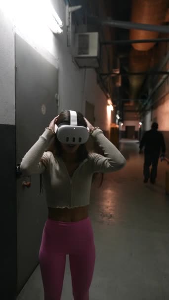 Egy gyönyörű fiatal nő elmerül a virtuális valóságban egy homályos szobában. Kiváló minőségű 4k felvételek - Felvétel, videó