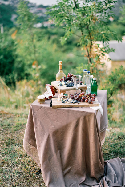 Il tavolo festivo con frutta su piatti e bottiglie di bevande sta in uno schiarimento. Foto di alta qualità - Foto, immagini