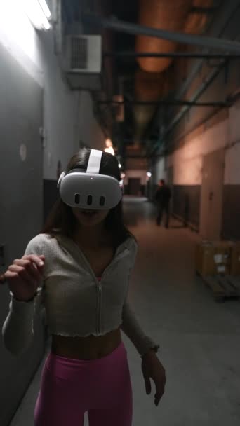 Una mujer impresionante con auriculares VR en una habitación débilmente iluminada. Imágenes de alta calidad 4k - Metraje, vídeo