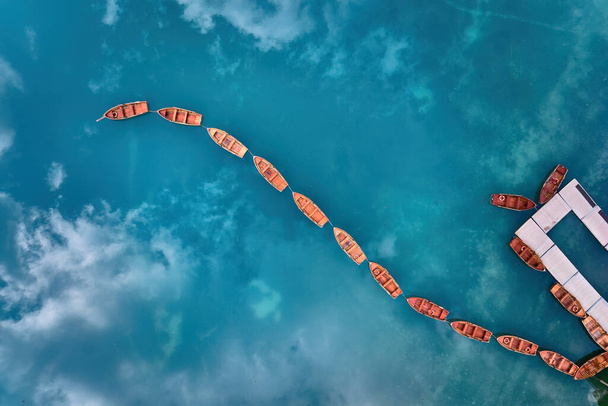 Uma vista artística, perpendicular de uma forma de eixo feito de barcos de madeira na superfície de água azul-verde do Lago di Braies nas Dolomitas. Ideal para projetos de cartazes. - Foto, Imagem