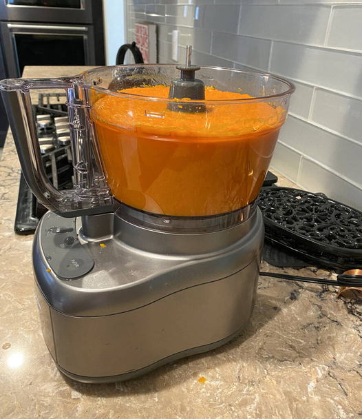 Um liquidificador cheio de líquido de abóbora laranja em cima de um balcão - Foto, Imagem
