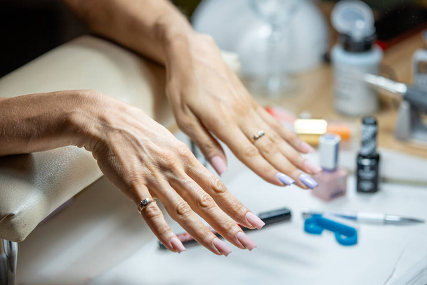Detailní záběr ženské ruky v nehtovém studiu na manikúře. Žena na manikúru nehtů v lázeňském centru. - Fotografie, Obrázek