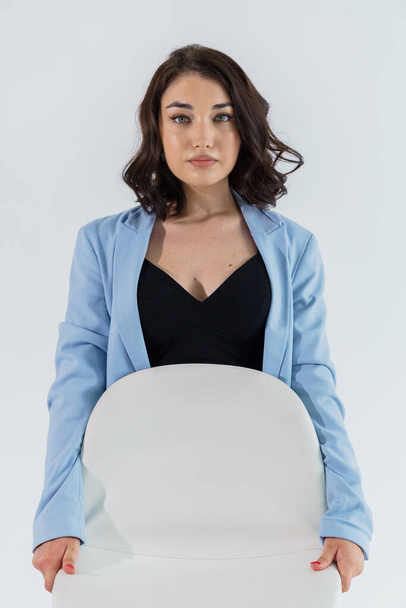 Beautiful young girl in black trousers and a blue jacket on a white background. Portrait of a young woman - Foto, immagini