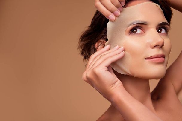 Kuva nainen koskettaa uusia kasvojen arkki naamio katso mainos pastelli tausta tekee ihon puhdas pehmeä. - Valokuva, kuva