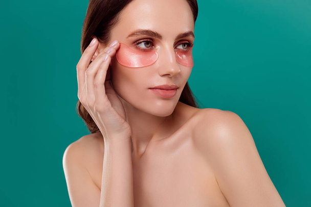 Photo portrait of attractive young woman touch face eye patches spa salon isolé sur fond de couleur cyan. - Photo, image