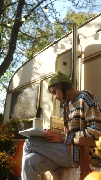 Kreatív hangulat az őszi parkban, ahol egy fiatal hippi lány táblagépet használ a munkájához. Kiváló minőségű 4k felvételek - Felvétel, videó