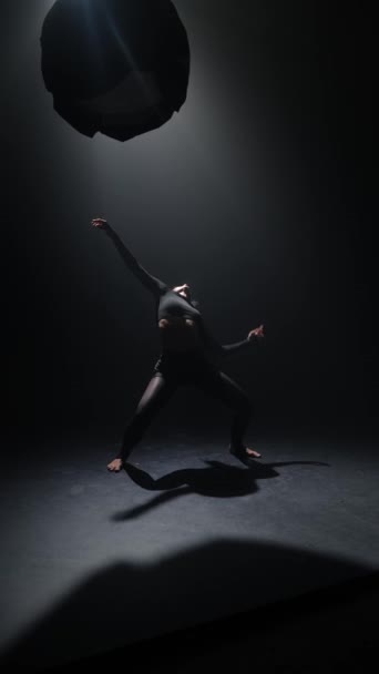 Dans eden çağdaş genç bir bayan loş bir stüdyoda zarifçe hareket eder. Yüksek kalite 4k görüntü - Video, Çekim