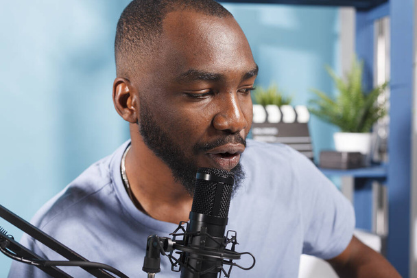 Blogger mluví do mikrofonu při nahrávání podcast vlog pro internetový kanál. Mladý africký Američan mluví v mikrofonu při streamování on-line v sociálních sítích - Fotografie, Obrázek
