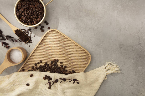 ブラウンは,ベージュの布とセメントの背景に木製のプロップで装飾されたコーヒー豆を焙煎しました. 化粧品のモックアップスペース. 広告のためのプロダクトそして昇進の概念 - 写真・画像