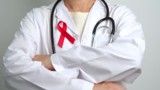 Doctor with Red Ribbon for December World Aids Day, acquired immune deficiency syndrome, multiple myeloma Cancer Awareness month and National Red ribbon week. Healthcare and world cancer day concept - Footage, Video