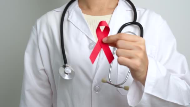 Médico con cinta roja para el Día Mundial del SIDA de diciembre, síndrome de inmunodeficiencia adquirida, mes de conciencia del cáncer del mieloma múltiple y semana nacional de la cinta roja. Salud y concepto del día mundial del cáncer - Metraje, vídeo