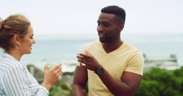 Toast, drinks and couple on holiday at ocean resort, hotel or celebration of interracial marriage. Smile, cheers and wine, happy man and woman on island vacation with love, travel and beach terrace - Footage, Video