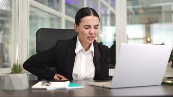 Képzett női vállalkozó zárt fekete kabát gépelés a modern számítógépes billentyűzeten, és tartsa a kezét az oldalon, miközben a fájdalom a tágas szobában. Az irodai munka fogalma és rossz közérzet. - Felvétel, videó