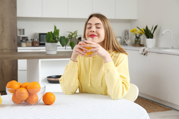 Mujer joven con vaso de jugo de naranja en la cocina
 - Foto, Imagen