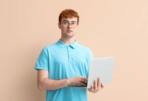 Программист-мужчина работает с ноутбуком на бежевом фоне - Фото, изображение
