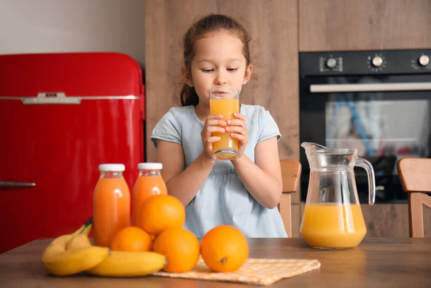 キッチンでオレンジジュースを飲む小さな少女 - 写真・画像