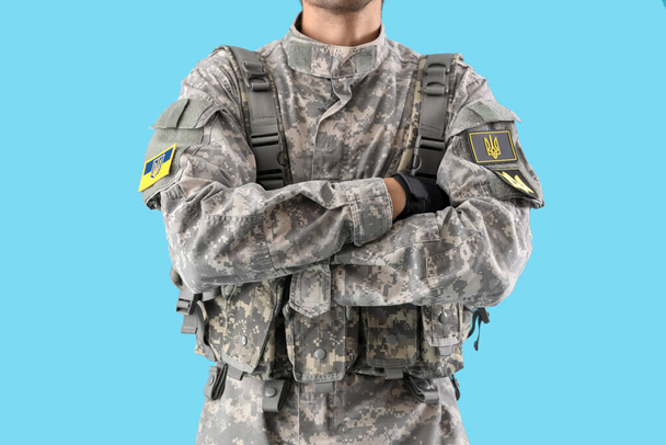 Солдат с украинскими шевронами на синем фоне - Фото, изображение
