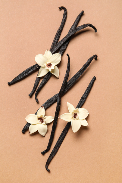 Ароматичні ванільні палички та квіти на коричневому фоні - Фото, зображення