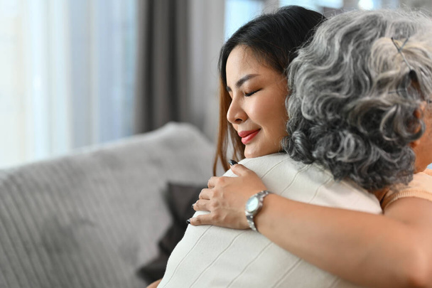 Любляча азіатська доросла дочка обіймає щасливу зрілу матір. Міжнародний день обіймів концепція. - Фото, зображення