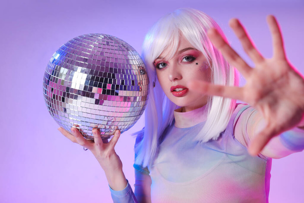 Schöne junge Frau mit Discokugel auf farbigem Hintergrund - Foto, Bild