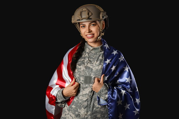 黒い背景に米国の旗を持つユニフォームの若い女性兵士 - 写真・画像