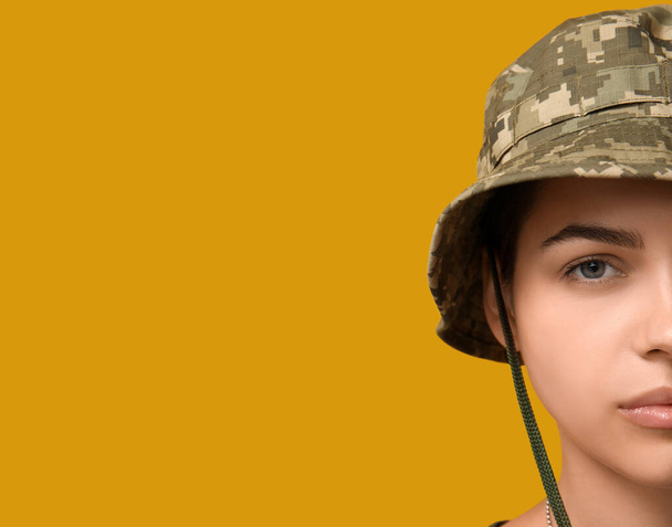 Soldado feminino jovem confiante em uniforme no fundo amarelo, close-up - Foto, Imagem