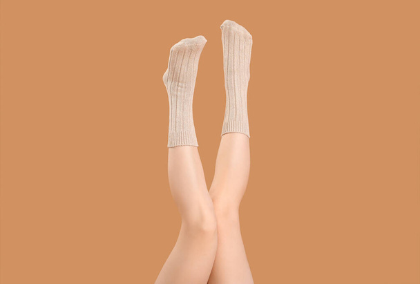 Πόδια από νεαρή γυναίκα σε πλεκτές κάλτσες σε μπεζ φόντο - Φωτογραφία, εικόνα