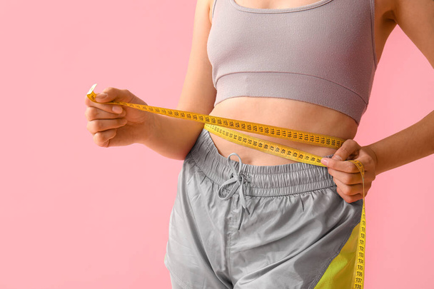 Schöne junge Frau mit Maßband auf rosa Hintergrund, Nahaufnahme. Konzept zur Gewichtsreduktion - Foto, Bild
