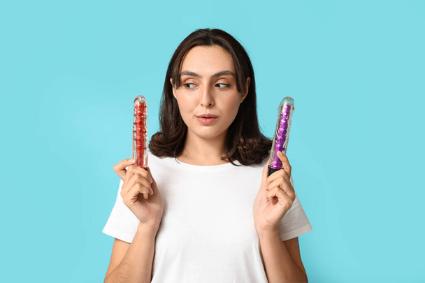 Beautiful young woman with vibrators on blue background - Photo, Image