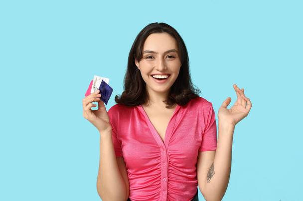 Mujer joven con condones sobre fondo azul. Concepto de sexo seguro - Foto, imagen