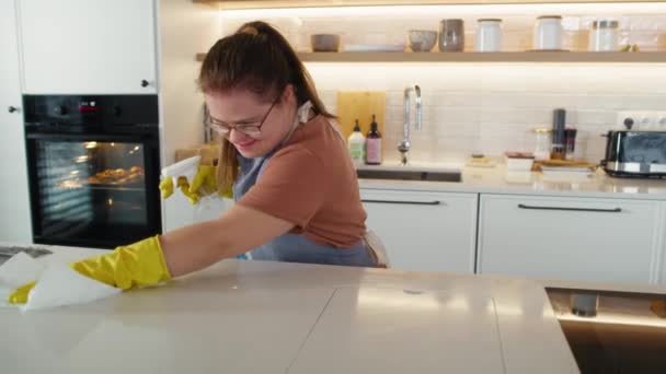 Downův syndrom žena čistí pracovní desku v domácí kuchyni. Snímek s RED heliovou kamerou v 8K.  - Záběry, video