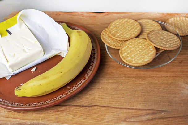 mantequilla congelada con galletas de plátano y plátano en una tabla de cortar de madera. flatlay - Foto, imagen