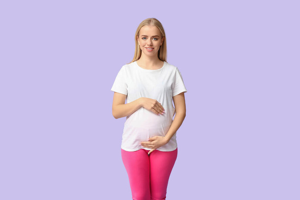 Молодая спортивная беременная женщина на фоне сирени - Фото, изображение