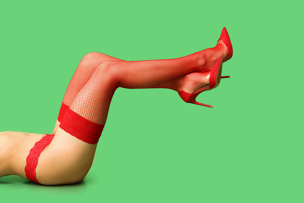 Las piernas de hermosa joven sexy mujer acostada sobre fondo verde, primer plano - Foto, imagen