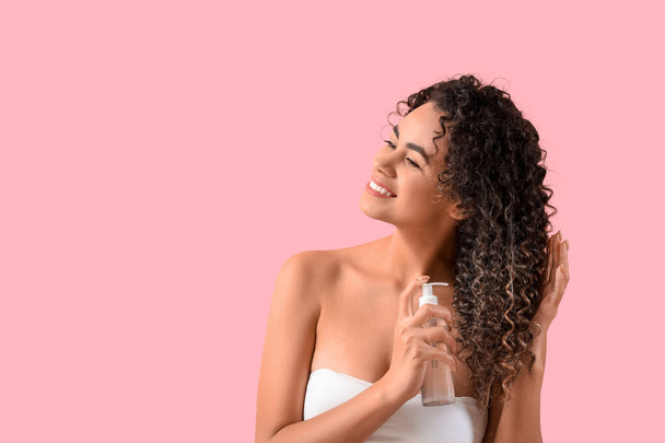 Красивая афроамериканка распыляющая волосы на розовом фоне - Фото, изображение